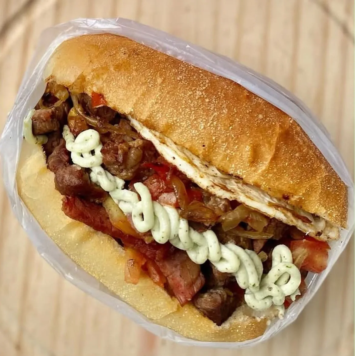 Sanduba artesanal do Vavá com carne, tomate, cebola e molho.